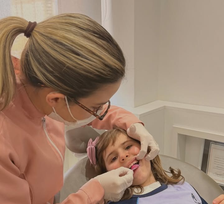 Dra. Karen Heiden colocando o aparelho cor-de-rosa em uma menina na cadeira do consultório